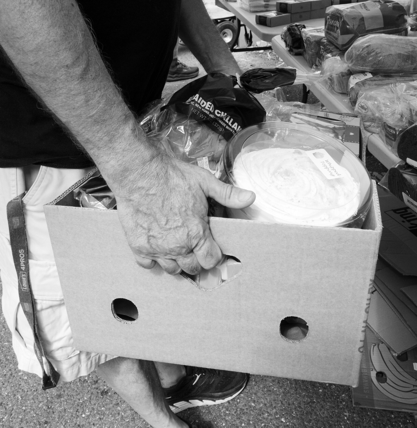 close up black and white of a person holding a food bank grocery box